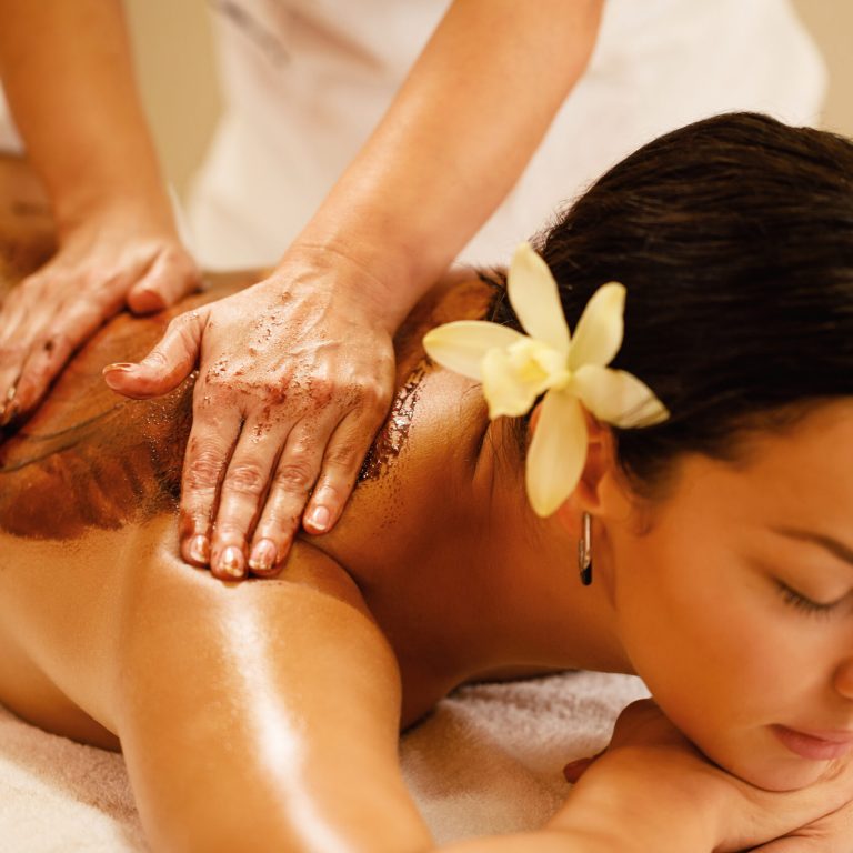 Close-up therapist massaging woman's back during hot chocolate spa treatment.